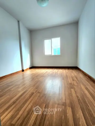 Spacious empty room with wooden flooring and natural light