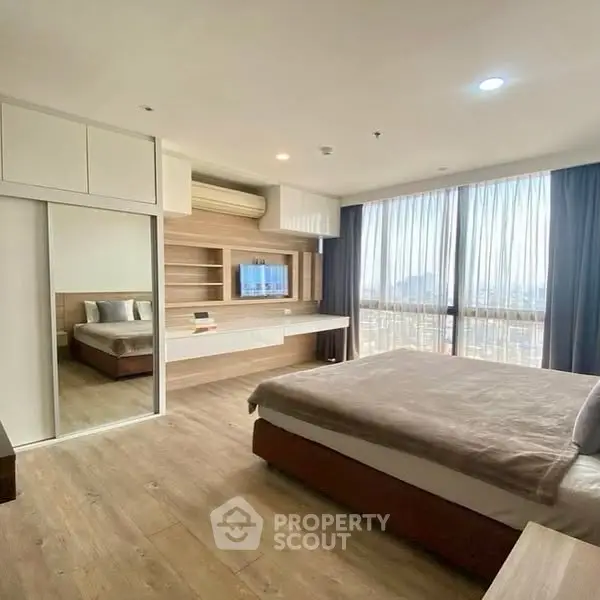 Spacious modern bedroom with large windows and wooden flooring