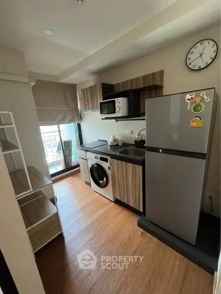 Modern kitchen with washing machine, fridge, and microwave in compact layout.