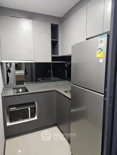 Modern compact kitchen with sleek grey cabinetry and stainless steel appliances