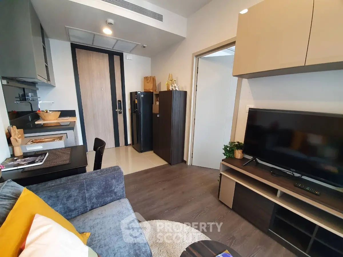 Modern living room with cozy sofa, TV unit, and compact kitchen in stylish apartment.