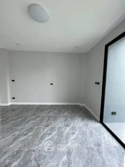 Spacious empty room with elegant marble flooring and large window for natural light.