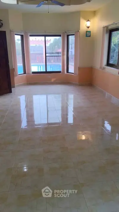 Spacious living room with large windows and pool view, perfect for natural light and relaxation.