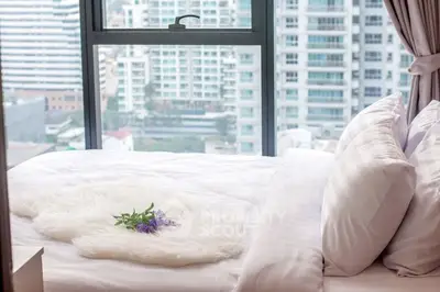 Luxurious bedroom with city view, featuring plush bedding and elegant decor.