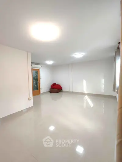 Spacious empty room with glossy tiled floor and natural light