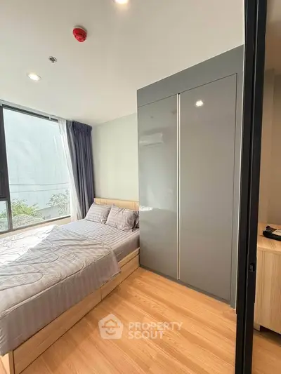 Modern bedroom with large window and sleek wardrobe in a stylish apartment.