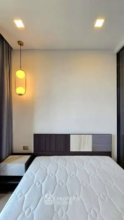 Modern bedroom with stylish lighting and minimalist decor, featuring a comfortable bed and elegant side table.