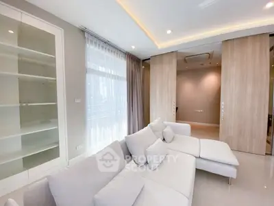 Spacious modern living room with elegant white sofa and large windows for natural light.