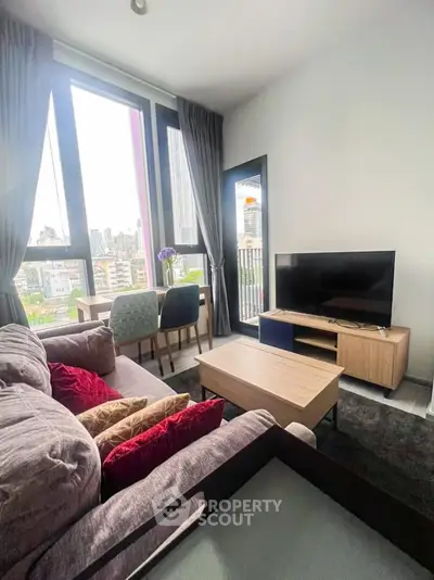 Modern living room with city view, cozy seating, and dining area in a high-rise apartment.