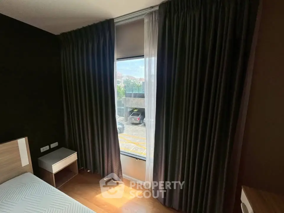 Cozy bedroom with large window and elegant curtains, offering a glimpse of the outside view.