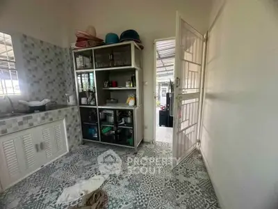 Charming kitchen with open door leading to outdoor area, featuring patterned tiles and ample storage.