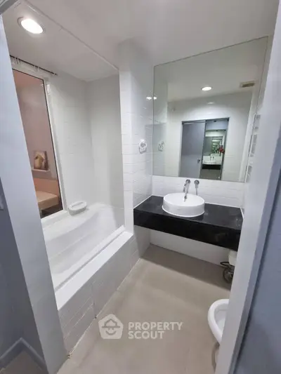 Modern bathroom with sleek design featuring a bathtub and stylish sink area.