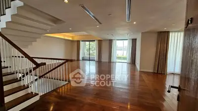 Spacious living room with wooden floors and modern staircase in luxury home