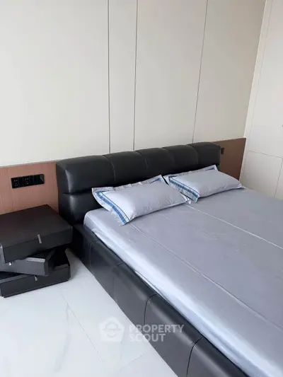 Modern bedroom with sleek black leather bed and minimalist design