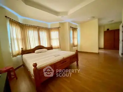 Spacious bedroom with wooden flooring and large windows for natural light.