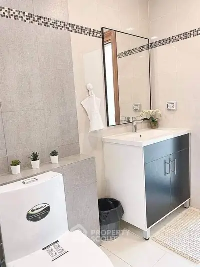 Modern bathroom with sleek vanity and decorative plants, perfect for a stylish home.