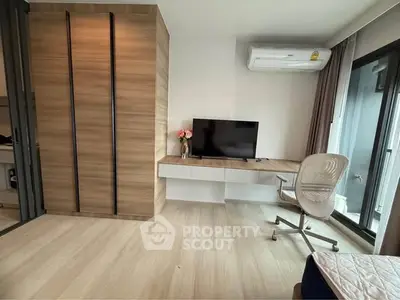 Modern bedroom with sleek wooden wardrobe and wall-mounted TV, featuring a stylish chair and air conditioning.