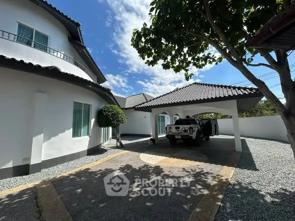 Charming suburban home with spacious driveway and carport under clear blue skies.