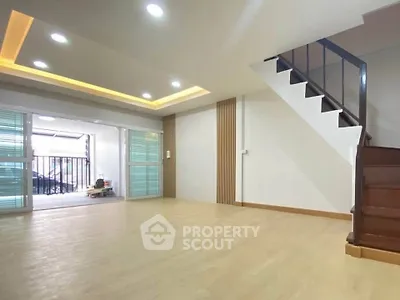 Spacious living room with modern staircase and large windows for natural light.
