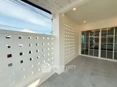 Modern balcony with stylish perforated wall and sliding glass doors