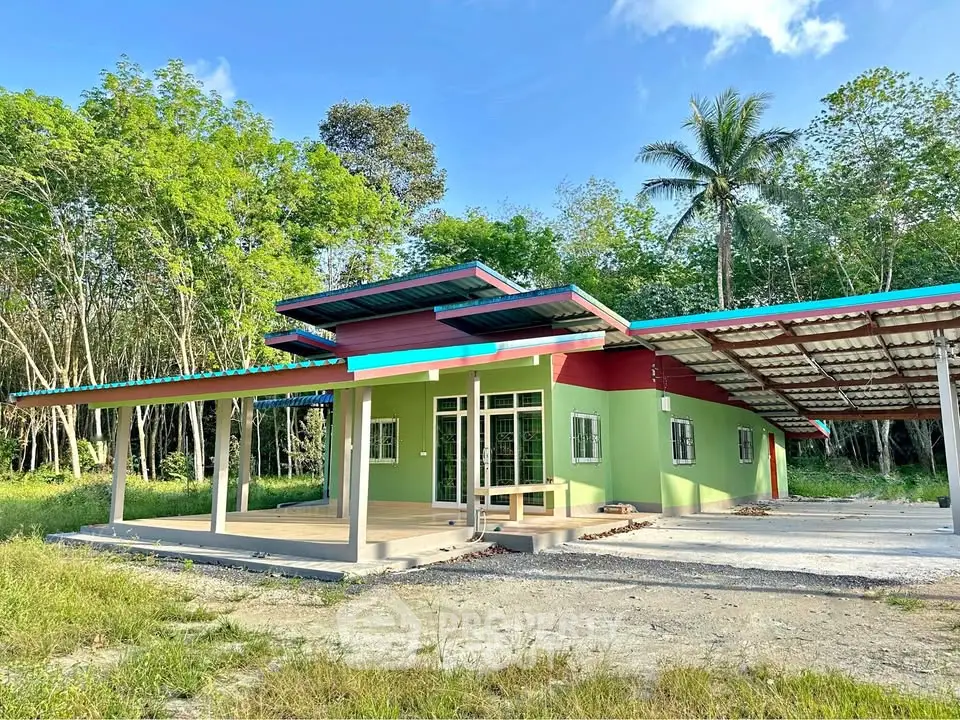 Charming modern house with vibrant green exterior and spacious carport set in lush greenery.