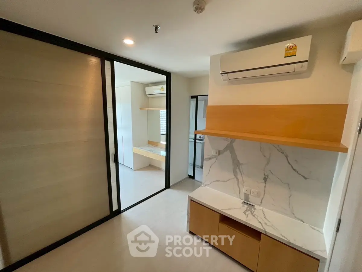 Modern apartment interior with sliding doors and air conditioning, featuring a sleek marble accent wall.