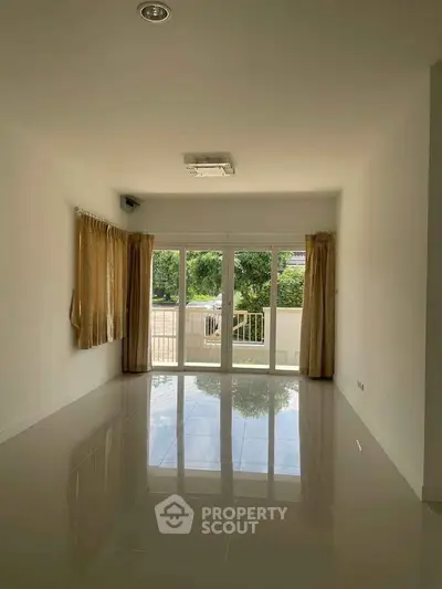 Spacious living room with large windows and glossy tiled floor, offering a bright and airy ambiance.