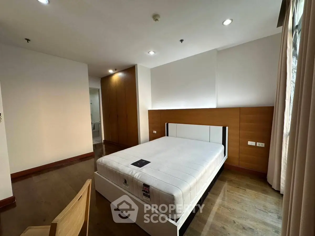 Spacious modern bedroom with wooden flooring and ample natural light.