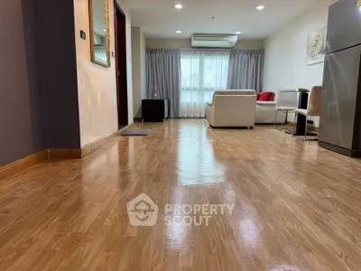 Spacious living room with wooden flooring and modern furniture, perfect for comfortable living.