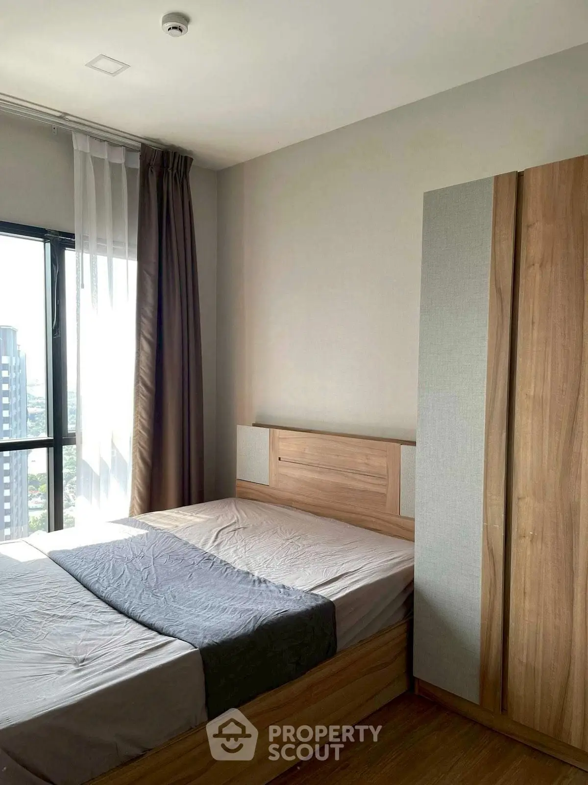 Modern bedroom with wooden furniture and city view, perfect for urban living.