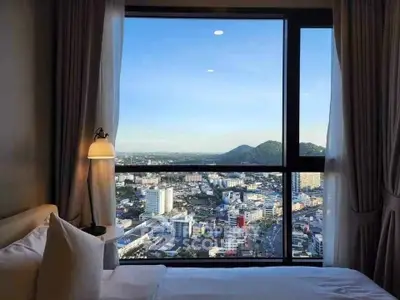 Luxurious bedroom with stunning cityscape view through large window, perfect for urban living.