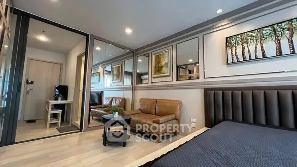 Modern bedroom with stylish decor and cozy seating area, featuring elegant wall art and sleek furnishings.