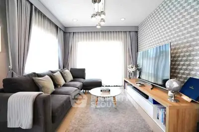 Modern living room with stylish decor, large TV, and cozy seating area.