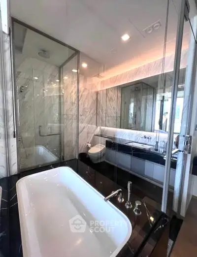 Luxurious modern bathroom with glass shower and elegant bathtub in high-end apartment.
