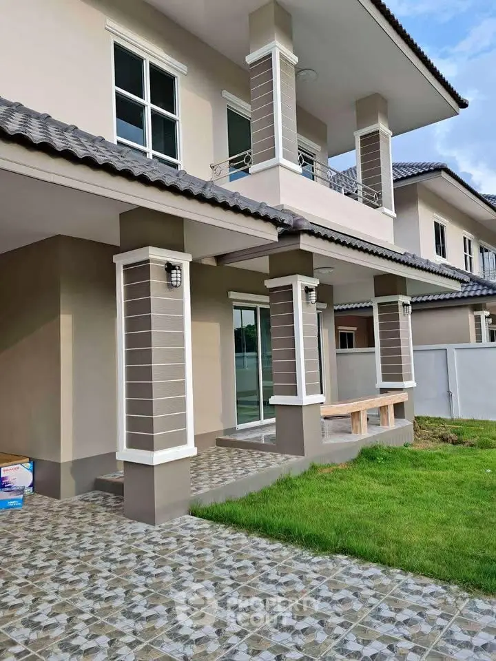 Modern two-story house with tiled patio and lush green lawn