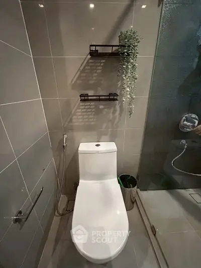 Modern bathroom with sleek toilet and glass shower enclosure, featuring elegant wall-mounted shelves.