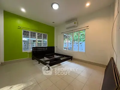 Spacious bedroom with green accent wall and large windows for natural light.