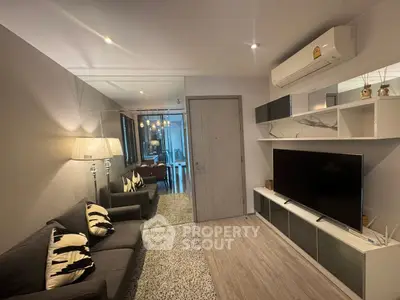 Modern living room with sleek design, featuring a large TV, stylish sofa, and elegant lighting.