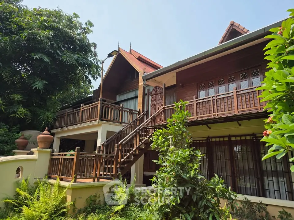 Charming traditional wooden house with lush garden and intricate balcony design.
