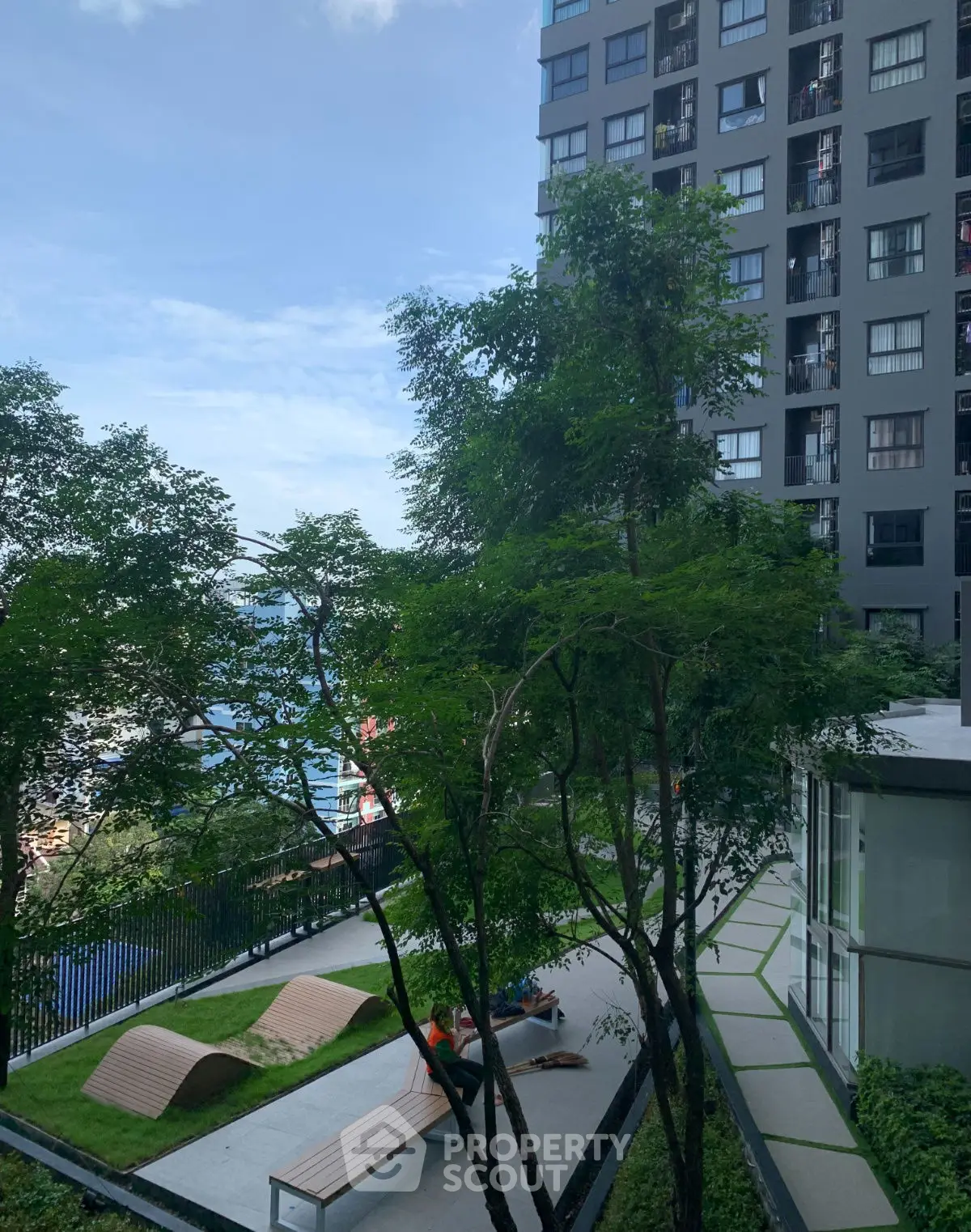 Modern apartment building with lush garden and seating area, perfect for relaxation.