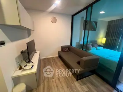 Modern living room with sleek design and glass partition leading to cozy bedroom.