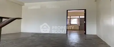 Spacious empty room with concrete floor and open doorway leading to another room.