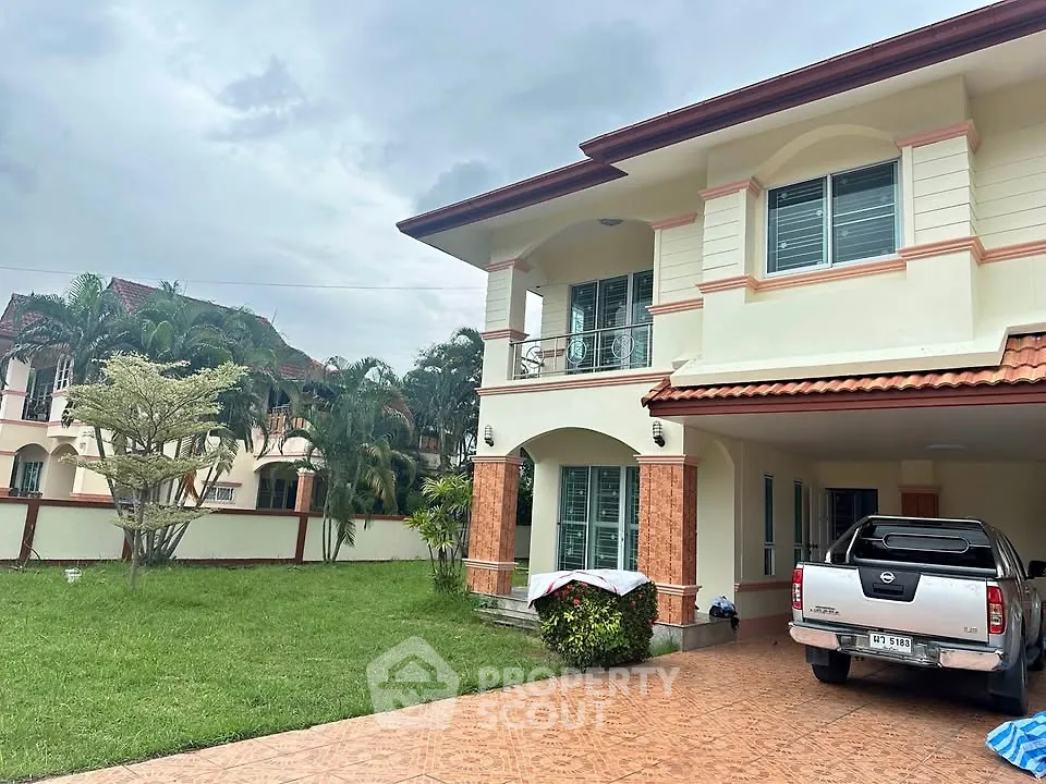 Spacious two-story house with lush garden and driveway in a serene neighborhood.