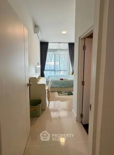 Modern bedroom with sleek design and natural light, featuring a cozy workspace and elegant decor.