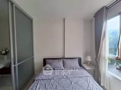 Cozy bedroom with modern decor and large window offering natural light