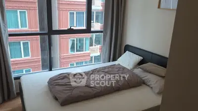 Cozy bedroom with large window and city view in modern apartment