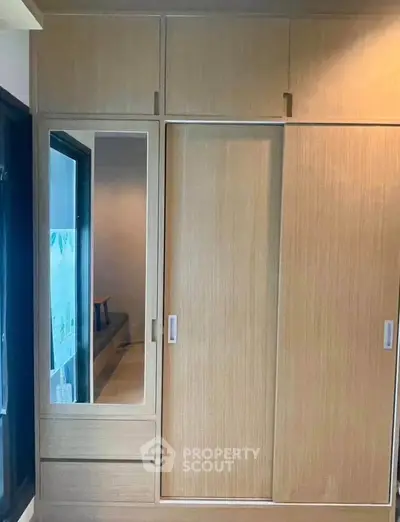 Modern wooden wardrobe with sliding doors and mirror in a stylish bedroom.