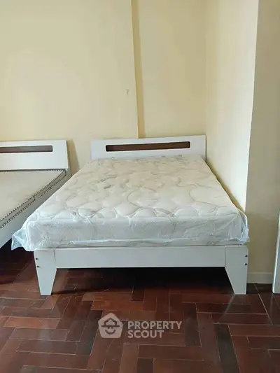 Cozy bedroom with wooden flooring and modern bed frame, perfect for restful nights.