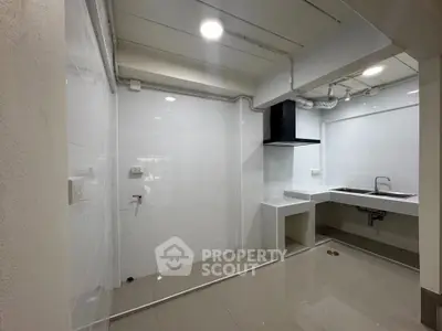 Modern kitchen with sleek white tiles and built-in sink, perfect for culinary enthusiasts.