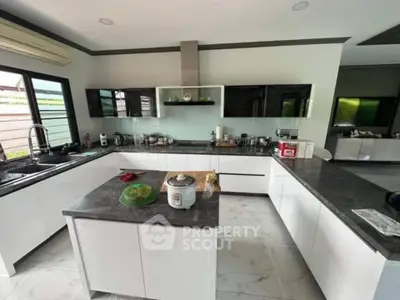 Modern kitchen with sleek white cabinets and island, featuring a gas stove and ample counter space.